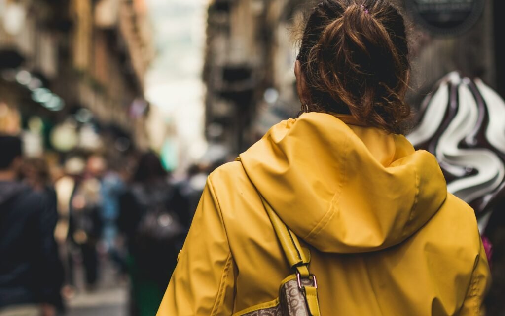 Donna con zaino impermeabile e giacca antipioggia in città